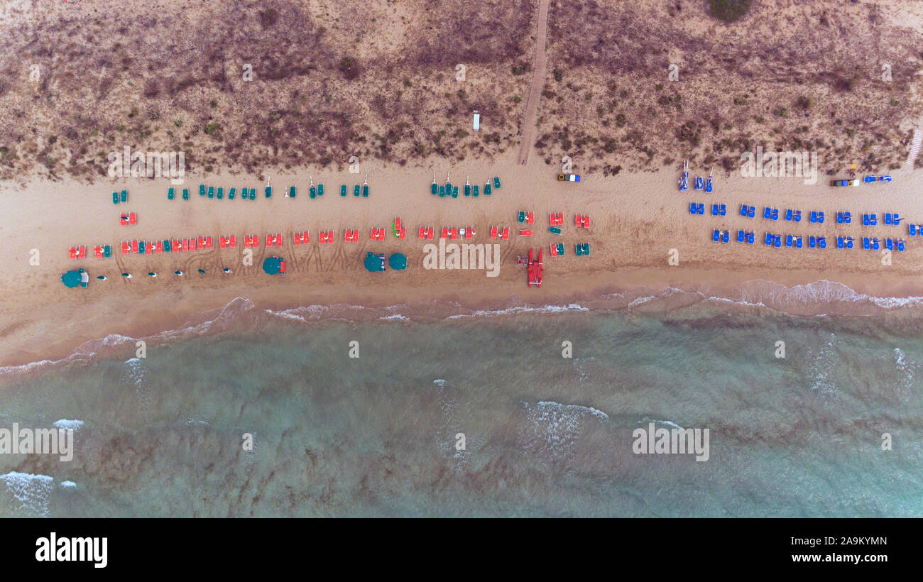 Luftaufnahme von Grün, Rot, Blau Schirme und Liegen liegen an einem Sandstrand mit flachem Meer Wasser. Stockfoto
