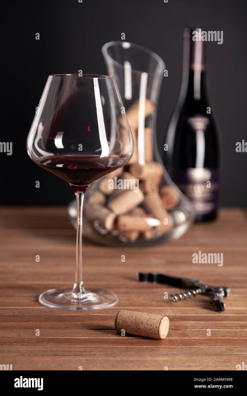 Crystal glänzend Rotwein Gläser, Flaschen, Korkenzieher, Flaschenöffner, Sommelier Messer, transparente Ölabscheider mit Korken auf hölzernen Tisch. Closeup, Vertikal, wählen Sie Stockfoto