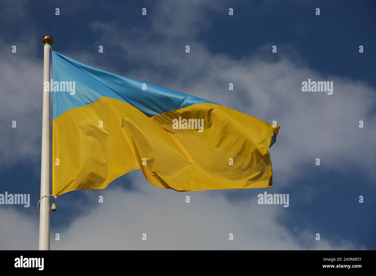 Flagge der Ukraine Wellen auf weißem Flaggenmast gegen den blauen Himmel mit weißen Wolken schön Stockfoto