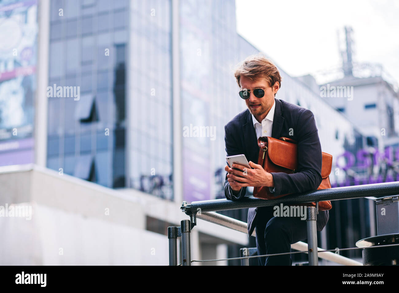 Ein junger, gut aussehender Geschäftsmann arbeitet unterwegs auf seinem Telefon Stockfoto