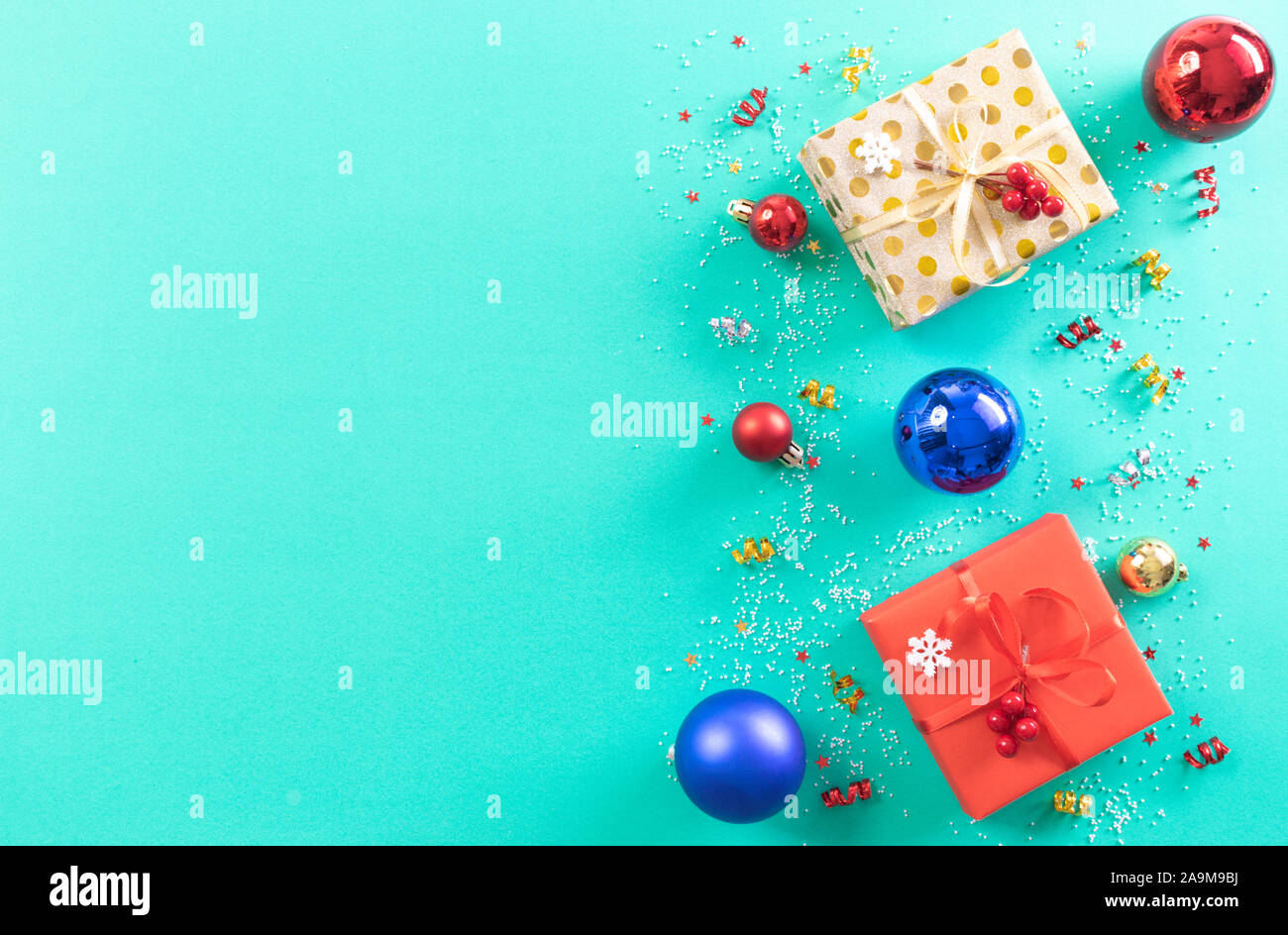 Weihnachten Hintergrund Konzept. Blick von oben auf die Weihnachten rot und gold Geschenkbox mit roten und blauen Dekoration und Glocke auf hellgrün Pastell Hintergrund. Kopieren Stockfoto