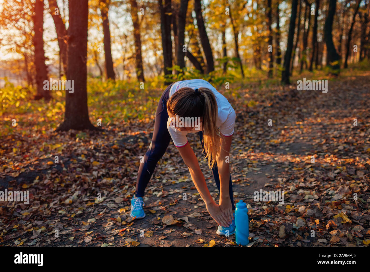 Ausbildung und Training im Herbst Park. Frau stretching Beine Bücken im Freien. Aktiv gesund Lifestyle Stockfoto