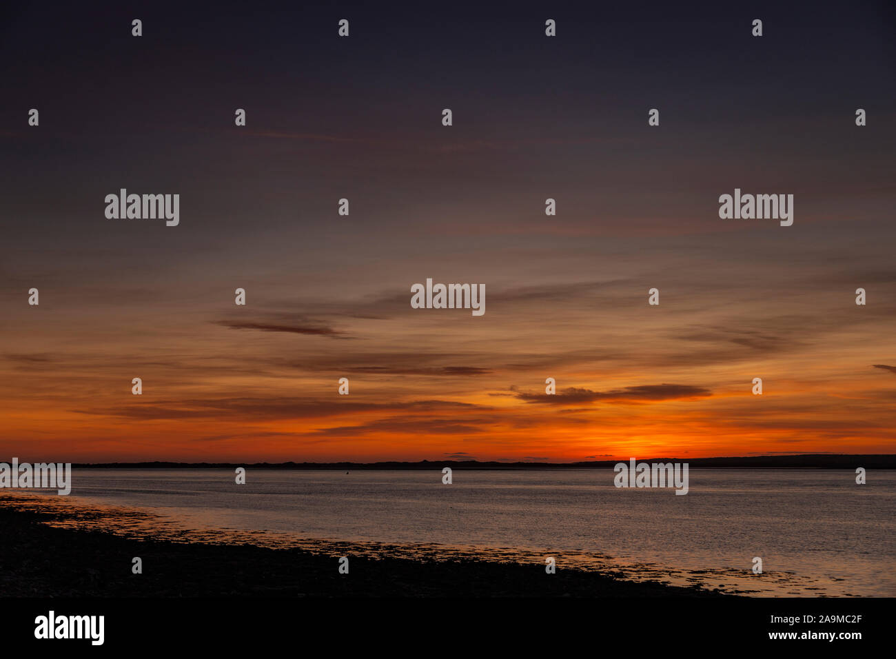 Sonnenuntergang über die Menai Straits von Caernarfon an der Küste von Nordwales Stockfoto
