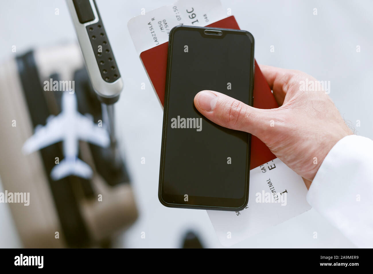 Die elektronische Registrierung per Smartphone an Bord des Flugzeugs. Ein Mann mit einem Koffer hält ein Telefon Ticket und Pass. Stockfoto