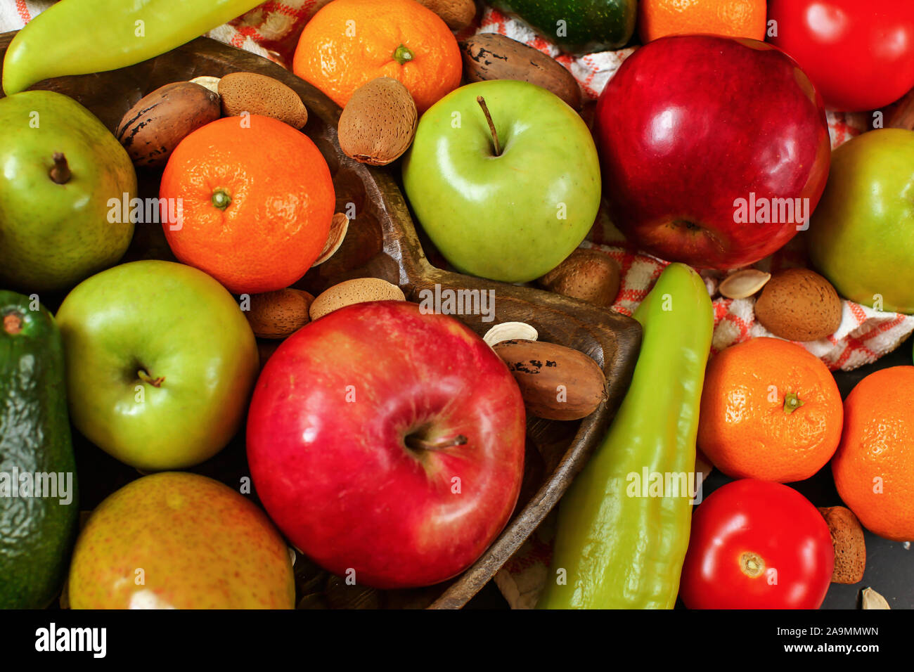 Gemischtes Obst und Gemüse - Paprika, Avocado, Äpfel, Birnen, Mandarinen, Pecan Nüsse, Mandeln und Kürbis Samen auf hölzerne Schüssel, Ansicht schließen Stockfoto