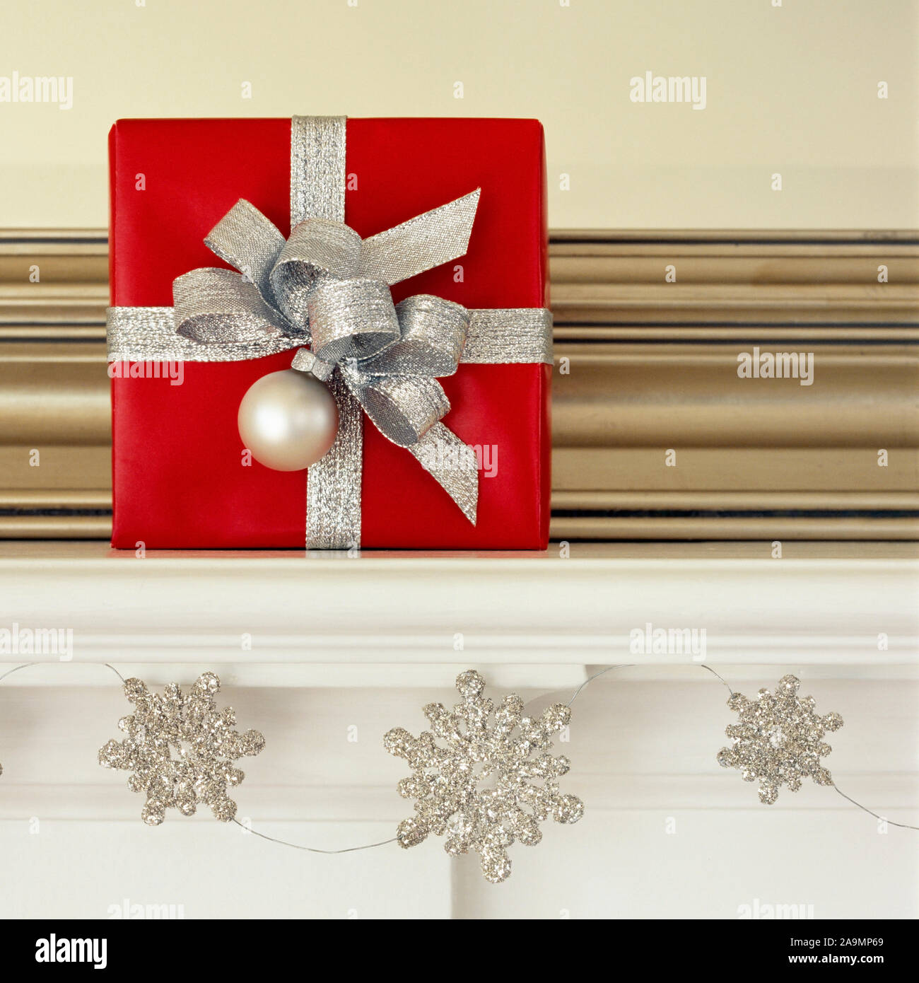 Lust auf Rot und Silber Weihnachtsgeschenk auf Wohnzimmer Mantel mit Glitzer Schneeflocke Girlande. Schönes, elegantes Ferienhaus Einrichtung Einrichtung Stockfoto