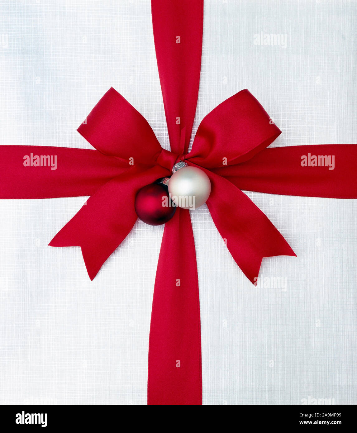 Nahaufnahme Nahaufnahme von Weihnachten Geschenk vorhanden mit leuchtend roten satin schleife und silber weiß Verpackung Papier. Einfache, grafische, modern, Weihnachten holida Stockfoto