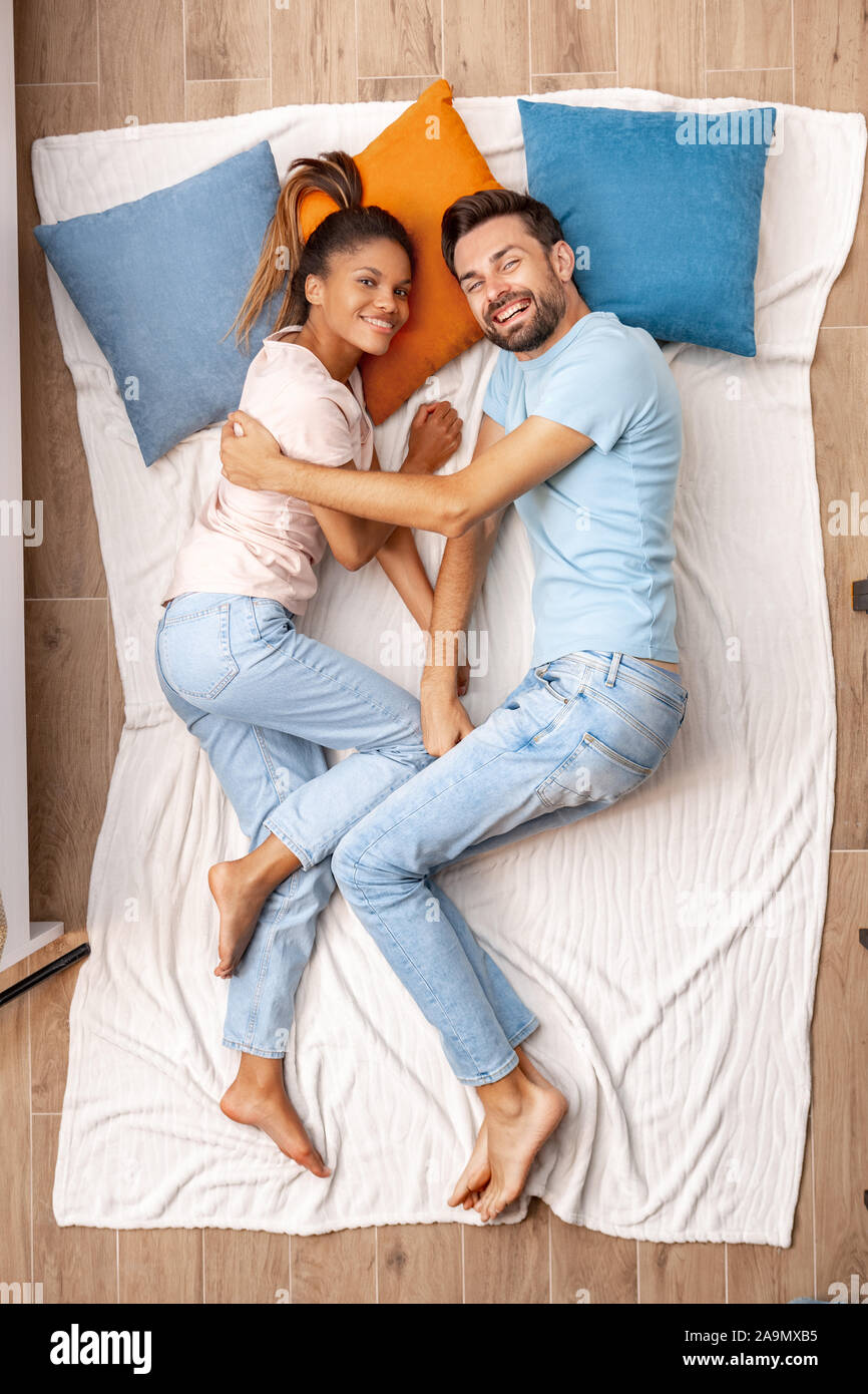 Junge erwachsene Frau und Mann auf dem Bett liegend zusammen und lächelte breit Stockfoto