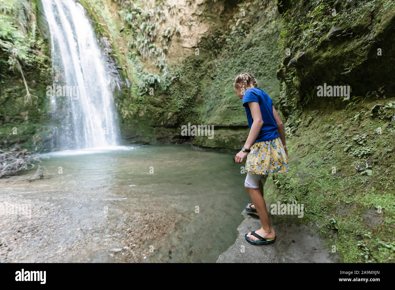 Jugendliche Mädchen steht auf einer Klippe mit Blick auf das Wasser unter Stockfoto