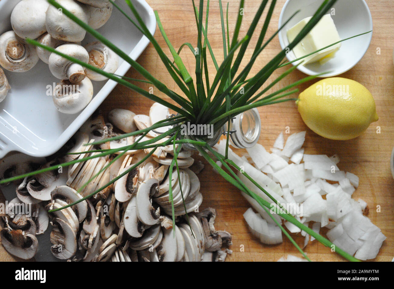 Schnittlauch von oben mit in Scheiben geschnittenen Champignons und Zwiebeln auf einem Holzbrett Stockfoto