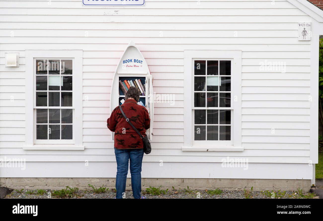 Frau Durchsuchen der wenig freie Bibliothek (Buch) in der Form eines Bootes, Castine, Maine, USA Stockfoto