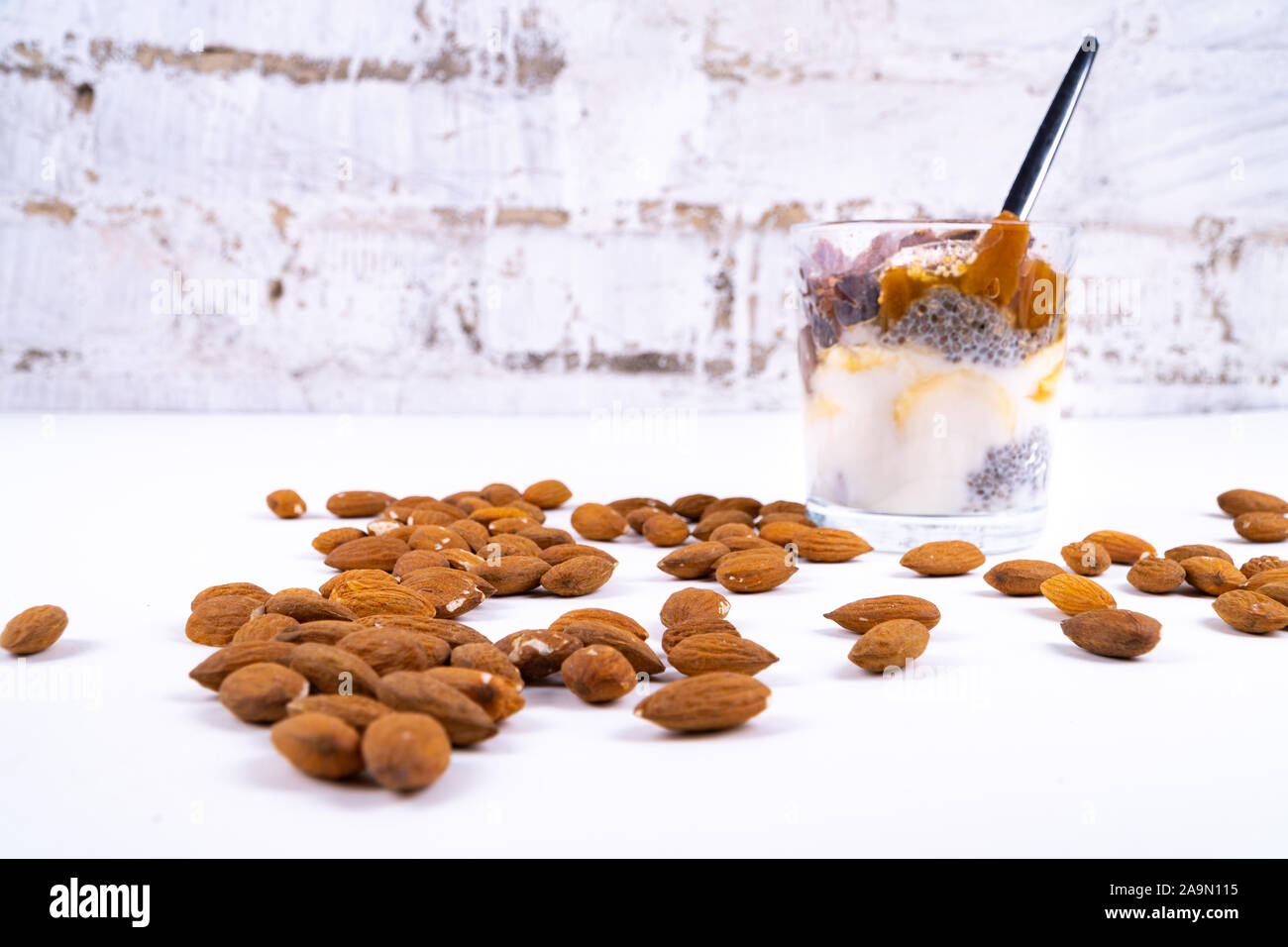 Eine vegane Wüste gemacht von Chia Pudding, Joghurt, Marmelade, Obst, Kekse und Mandeln auf weißem Hintergrund - Schrägansicht Stockfoto