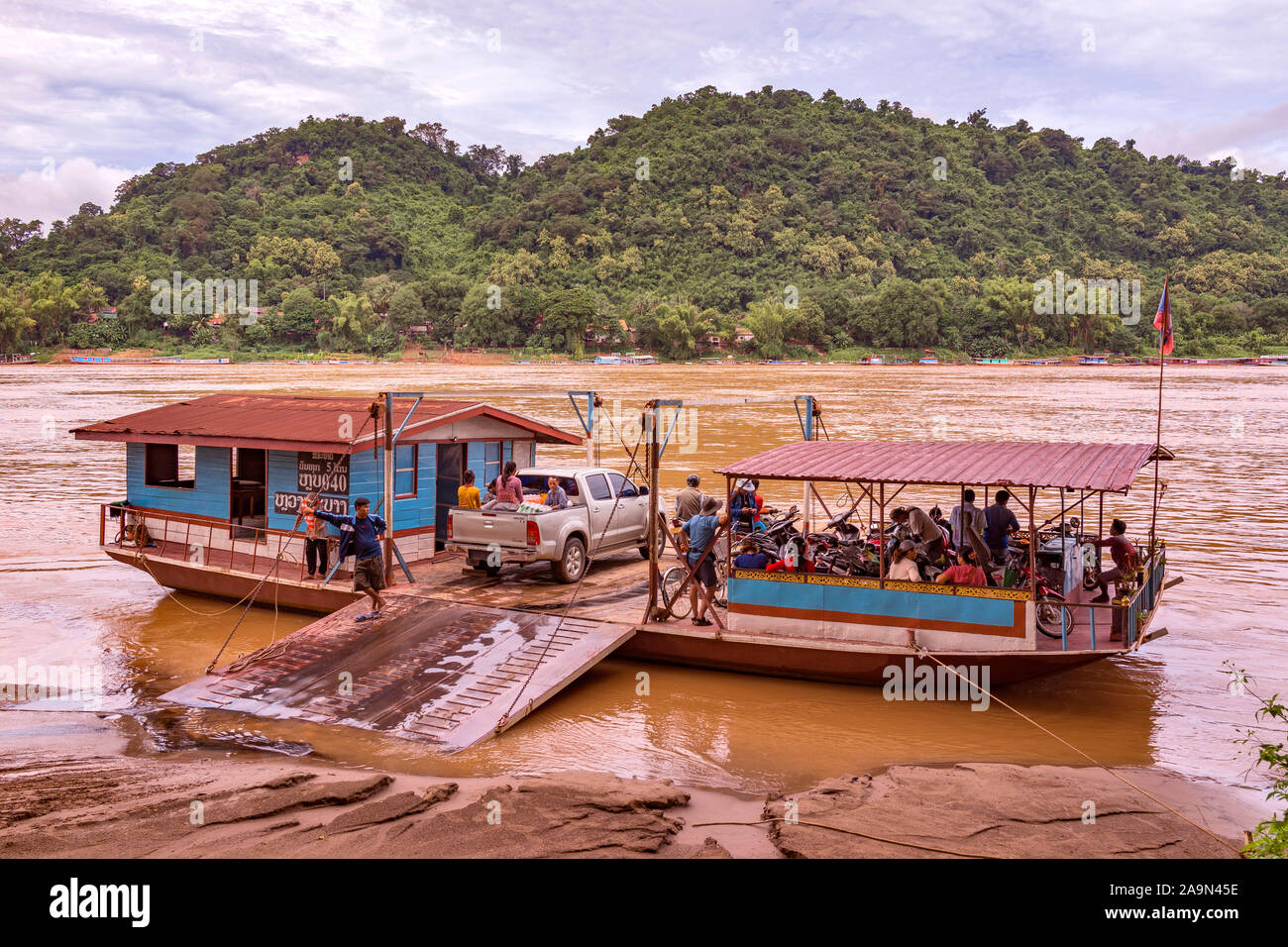 Eine geladene Autofähre auf dem mächtigen Mekong-Fluss in der malerischen zum Weltkulturerbe gehörenden Stadt Luang Prabang in Laos, Südostasien. Stockfoto