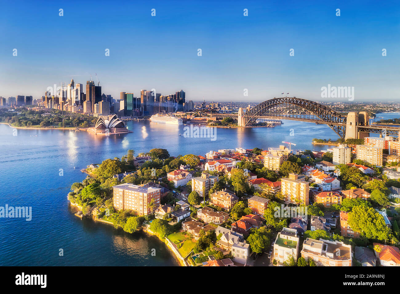 Gewässer des Hafens von Sydney, zwischen Stadt CBD Wahrzeichen kannonen von der Sydney Harbour Bridge zu North Shore reichen Vororte - erhöhte Antenne angeschlossen Stockfoto