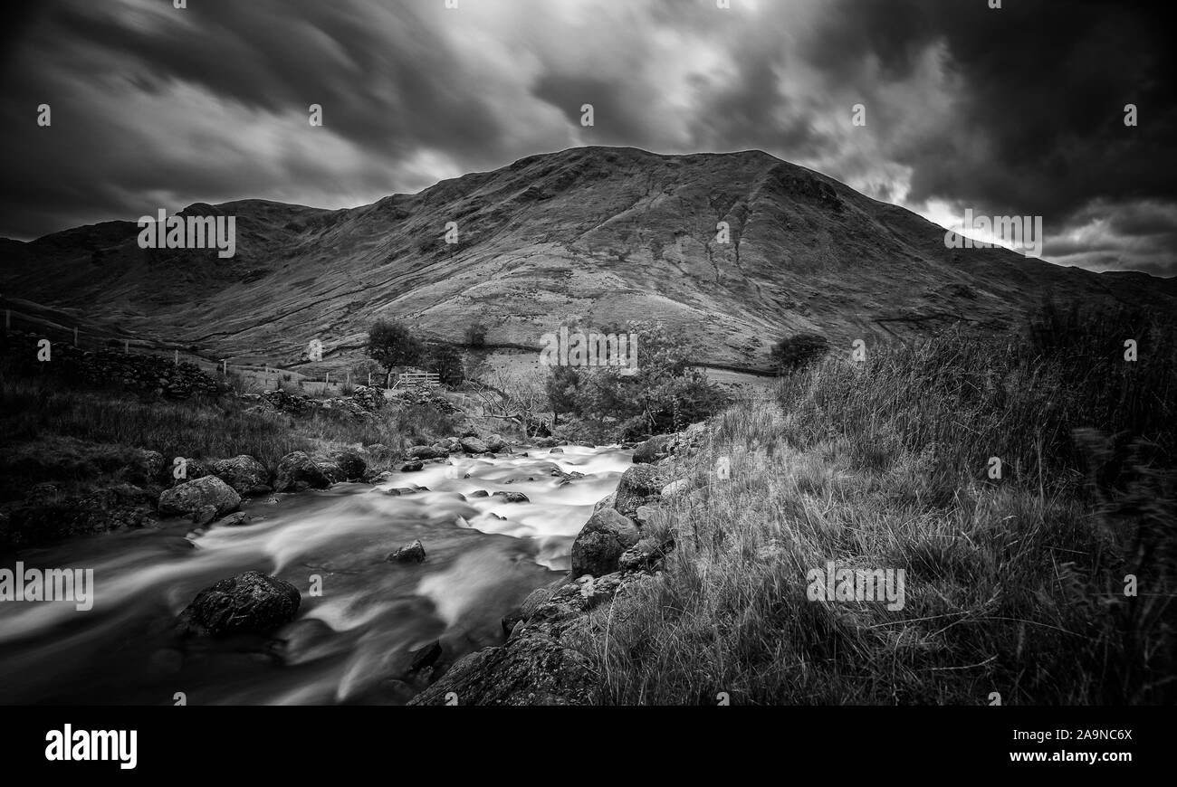 Lange Belichtung Schießen von Mountain Creek im malerischen Tal im Herbst. Nationalpark Lake District in Großbritannien - Monochrom bearbeiten Stockfoto