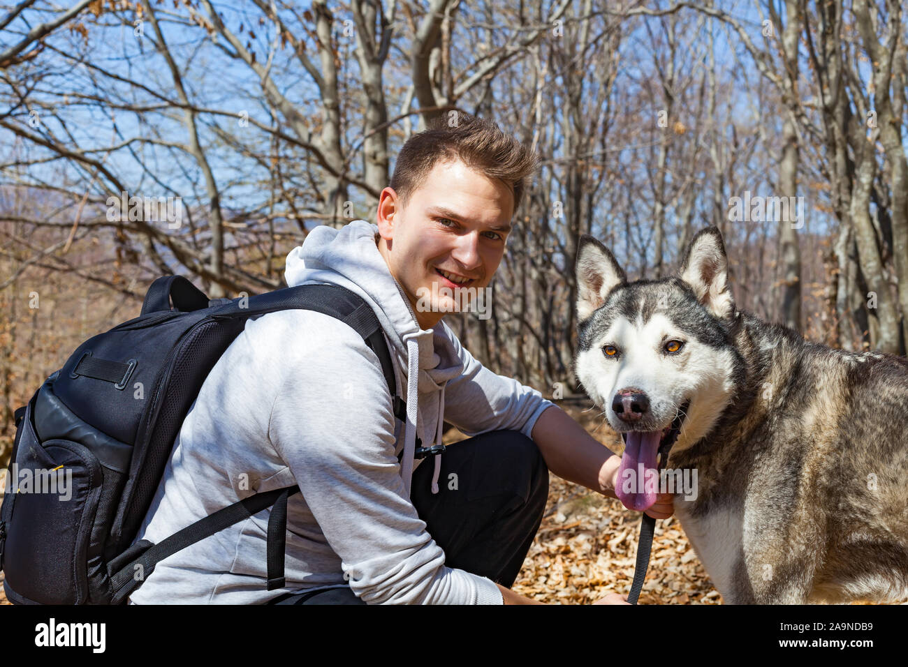 Junger Mann Wandern mit seinem Hund an einem sonnigen Tag, um die Kamera schaut Stockfoto