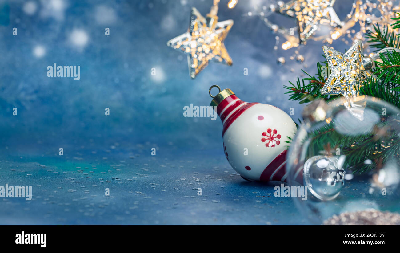Weihnachtsbaum Glas Kugeln, Sterne leuchten Garland und Tannenzweigen auf blauem Hintergrund Stockfoto