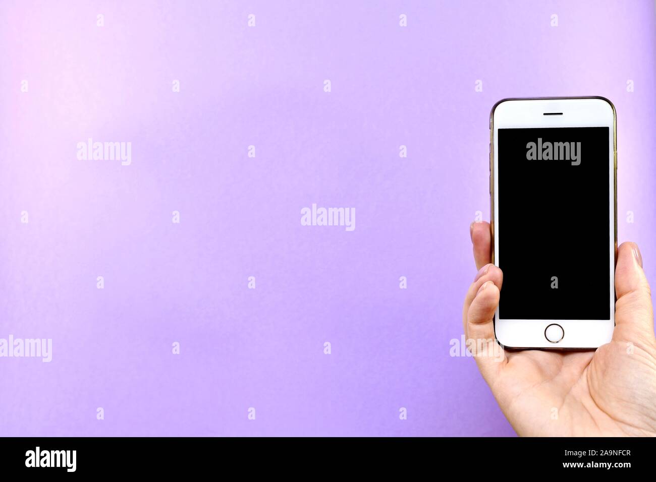 Smartphone mit einem schwarzen Bildschirm in der Hand gedreht, auf einem violetten Hintergrund. Stockfoto
