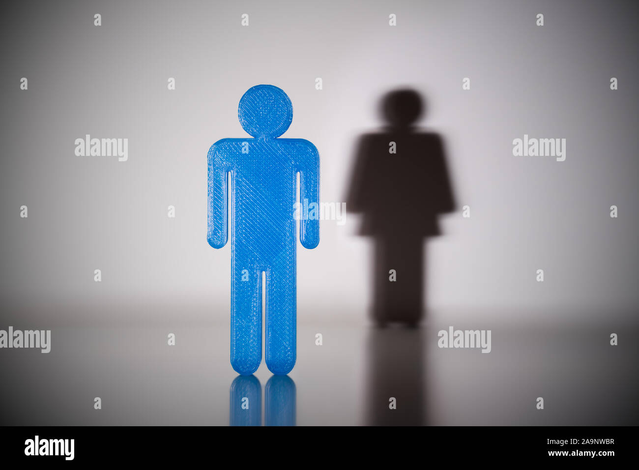 Blau Geschlecht Männlich menschliche Figur mit Schatten des weiblichen Geschlechts menschliche Figur an der Wand Stockfoto