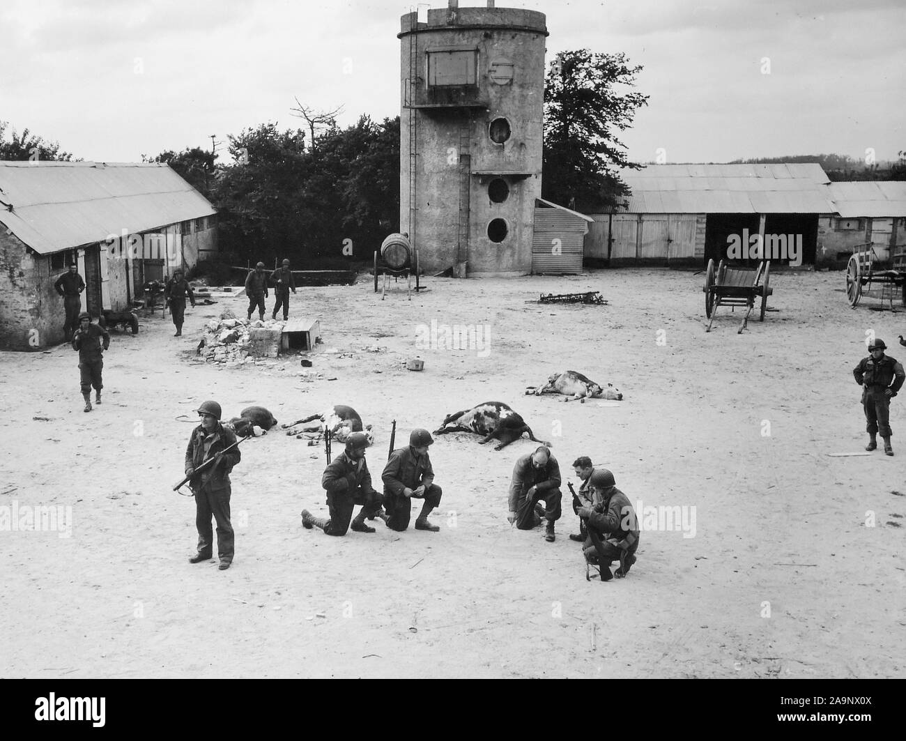 [ORIGINAL CAPTION] Invasion der Alliierten in Frankreich... Im Hof eines Bauernhauses sie gerade der Deutschen Scharfschützen gelöscht haben, die amerikanischen Truppen planen den Angriff der nächsten Ziel auf dem Weg zum Sieg, auf einen Brückenkopf von Frankreich. Juni 10, 1944. Les Dunes De Varredille [Varreville]. Stockfoto