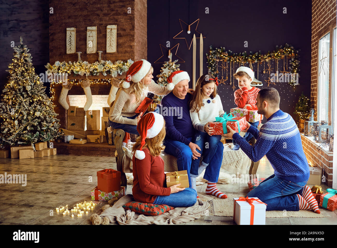 Eine große Familie in einem Zimmer gibt Geschenke zu Weihnachten. Stockfoto