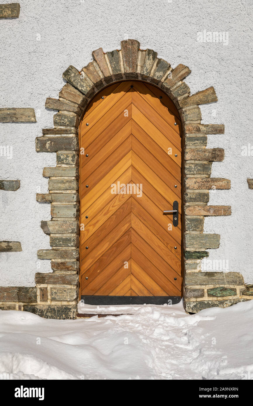 Hölzerne Tür auf weißes Gebäude dekoriert von birck mit Schnee im Winter. Stockfoto