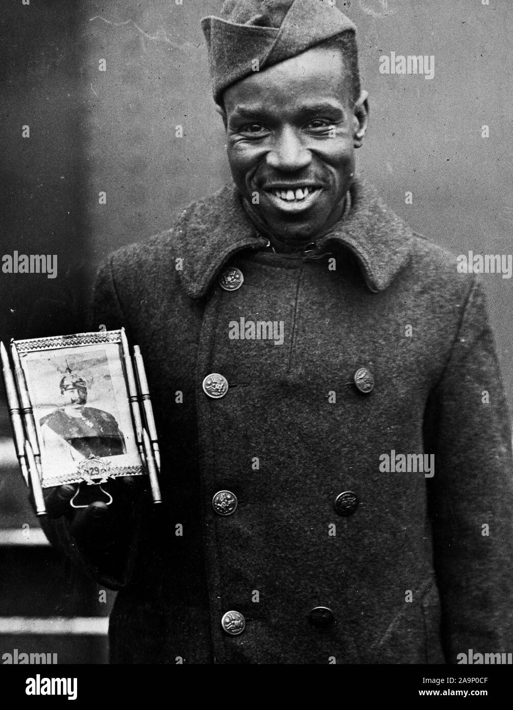 WW ich Fotos - Farbig/Afrikanische amerikanische Truppen - Kaiser's Bild als Talisman. Corporal Fred Mcintyre, als Mann des Teufels, gerade mit 369 Infanterie (NY farbige 15.) Auf der Stockholm und Foto der Kaiser, dass er für Glück 2/12/1919 durchgeführten Stockfoto