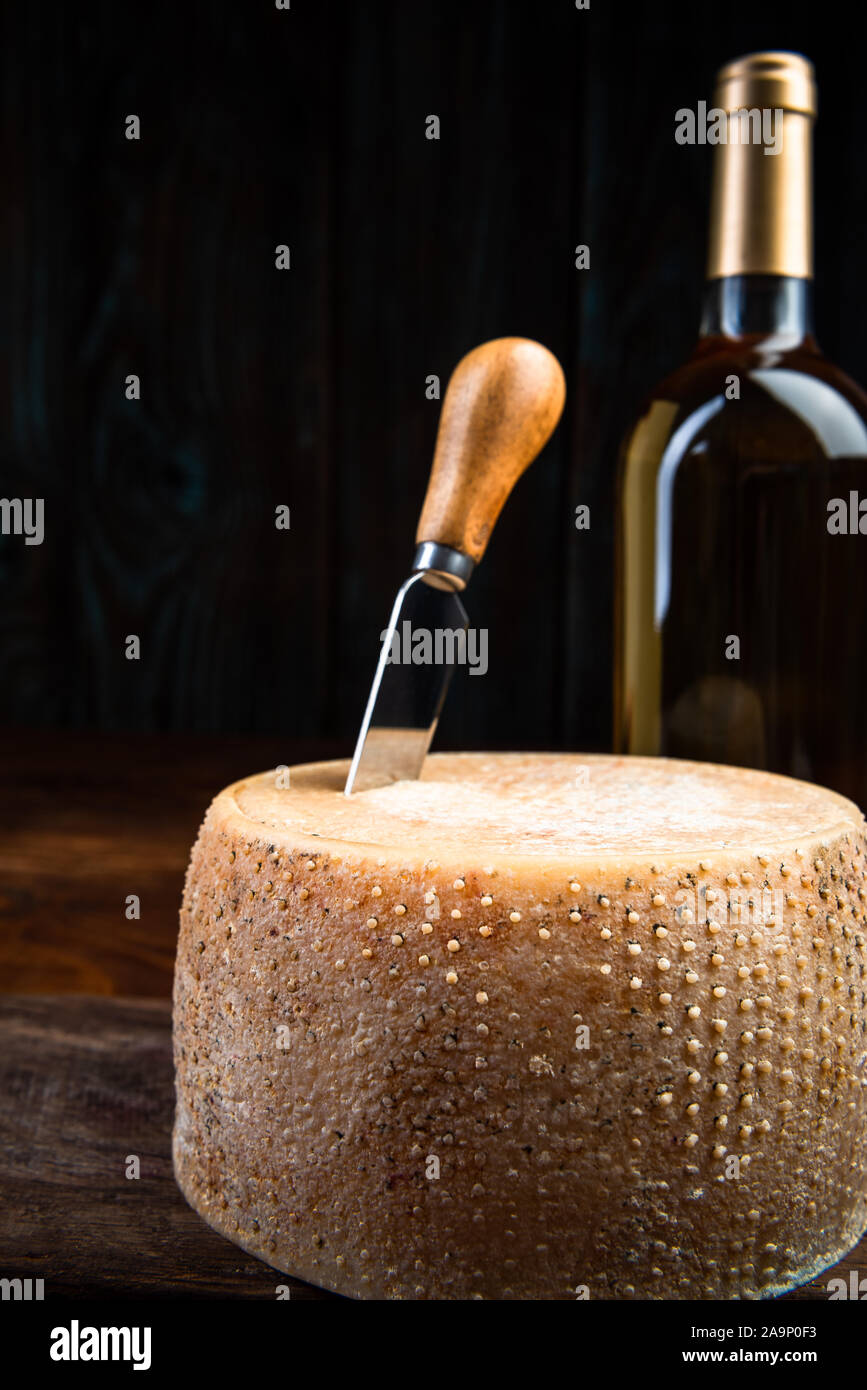 Hartkäse Rad reifte in Tagebuch Keller mit weißen Wein Flasche. Lokale Traditionelle produzieren. Stockfoto