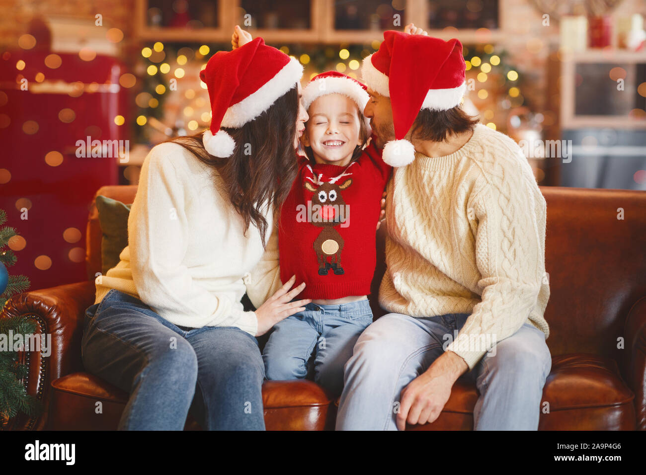 Santa Eltern küssen glücklich, kleines Mädchen, feiern Weihnachten zusammen Stockfoto