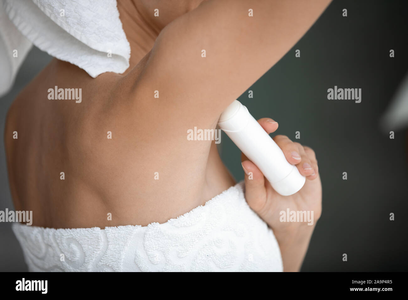 Junge Dame in Weiß Handtuch eingewickelt Antitranspirant in Achselhöhle anwenden Stockfoto