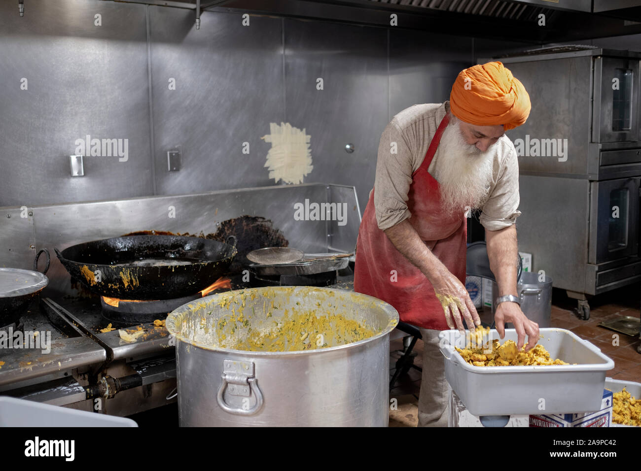 Ein Freiwilliger in einer langar, einem Sikh Tempel Küche, bereitet Pakora, ein frittiertes indische vegetarische. Snack. In South Richmond Hill, Queens, New York City. Stockfoto