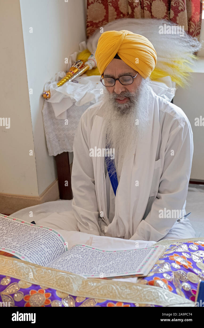 Ein Sikh Priester in einem turban liest aus dem Guru Granth Sahib heiligen Buch an einem Tempel in Richmond Hill, Queens, New York City. Stockfoto