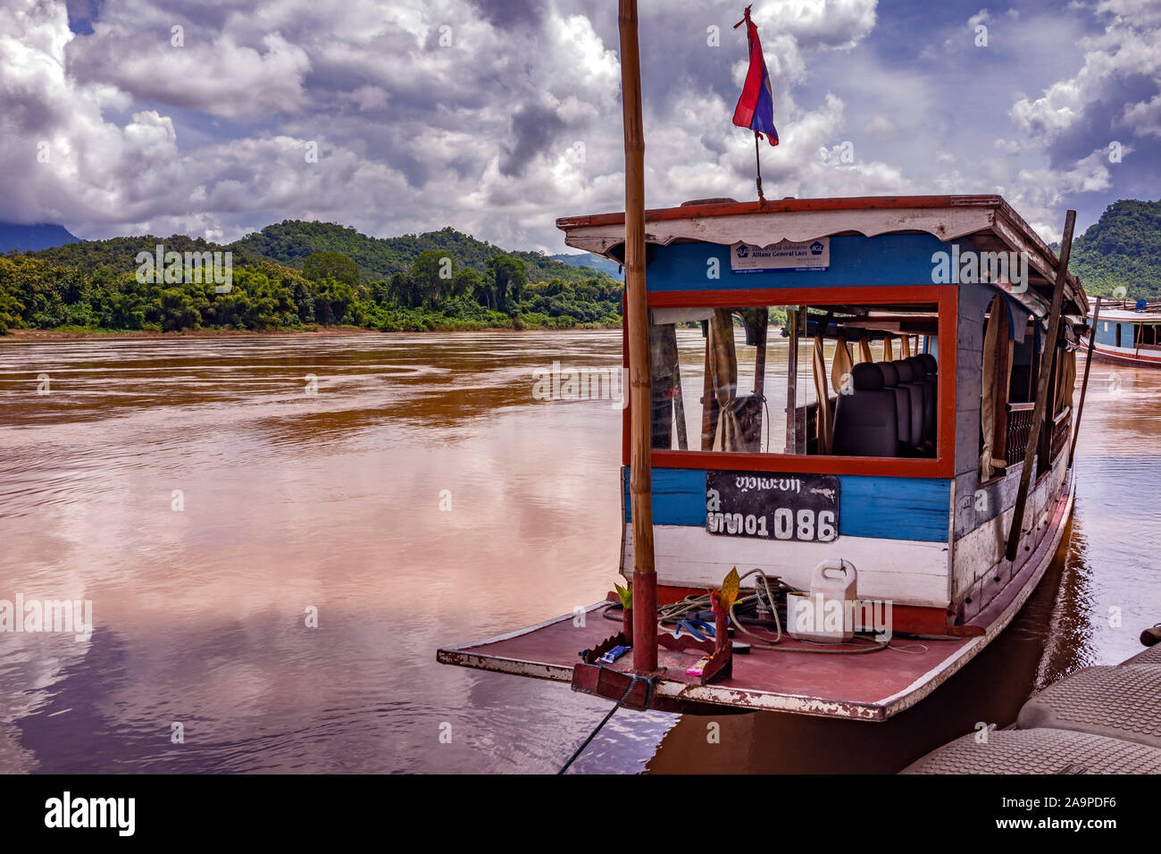 Der mächtige Mekong schlängelt sich durch die zum Weltkulturerbe gehörende Stadt Luang Prabang in Laos. Ein lokales Boot ist im Vordergrund. Stockfoto