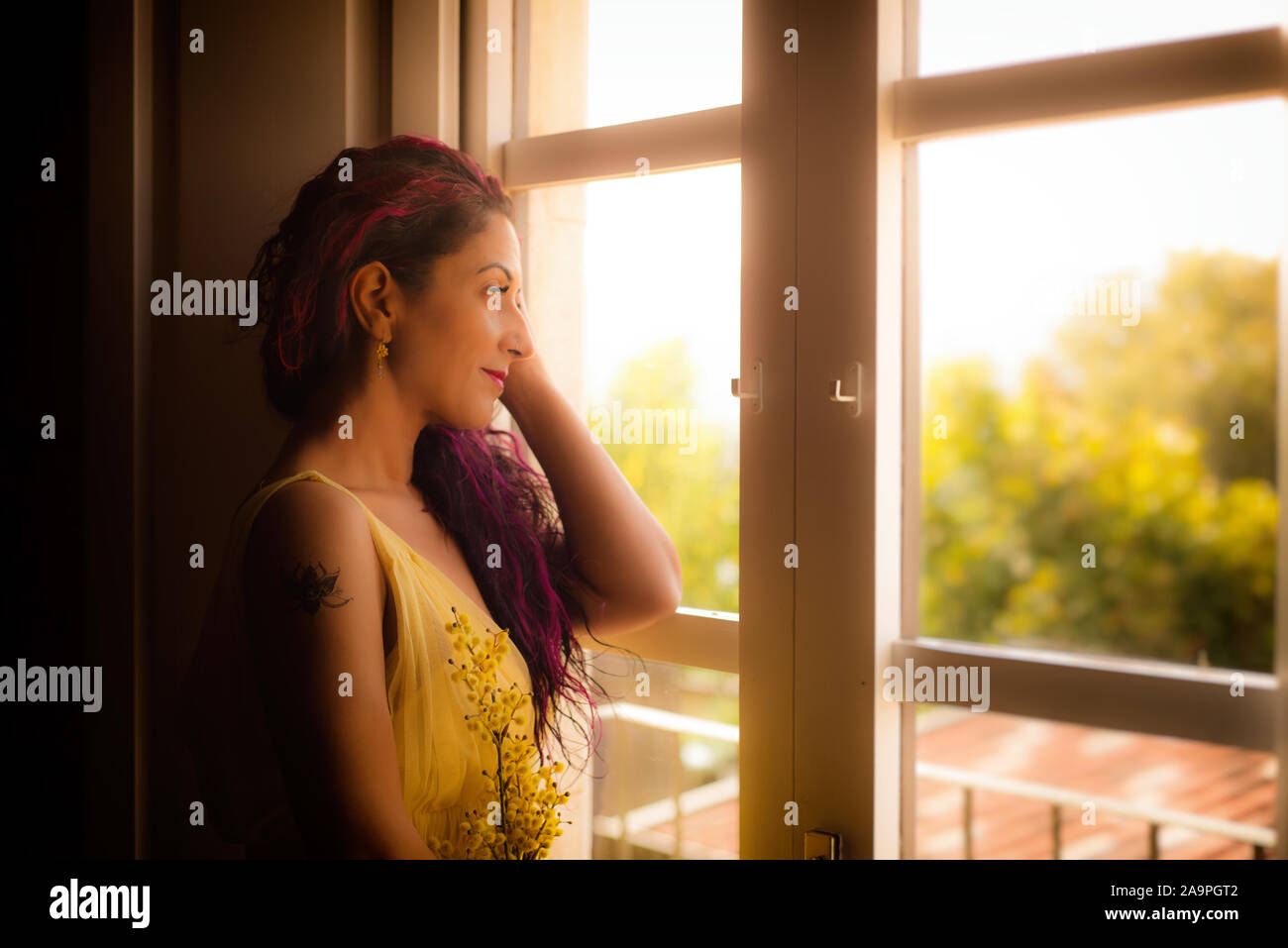 Eine Frau in gelb Hochzeit Kleid Kleid durch ein Fenster, eine Hand gegen den Kopf. Stockfoto