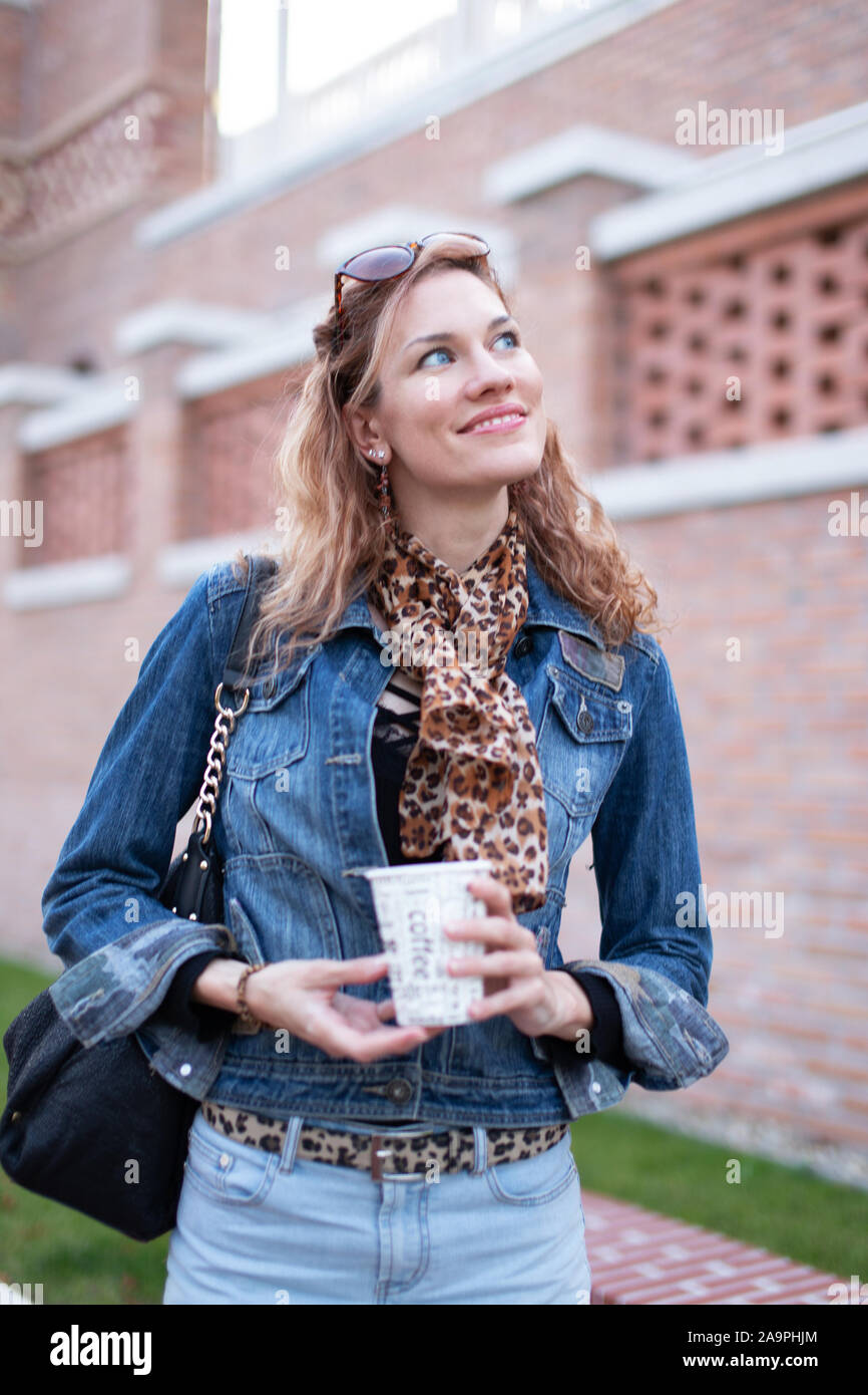 Glückliche junge urbane Frau mit Kaffee Weg suchen, positivität Stockfoto