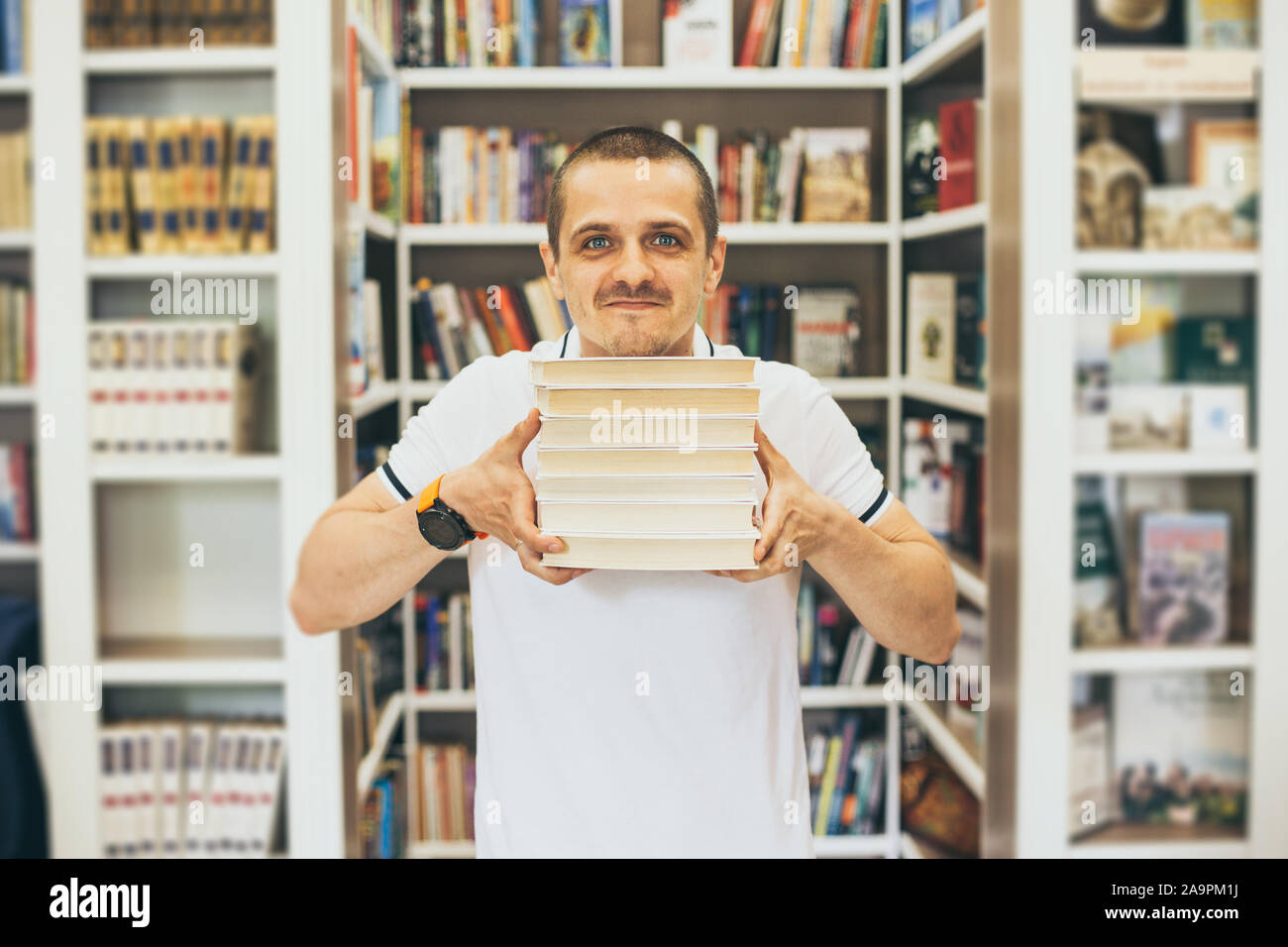 Mann im weißen T-Shirt Holding wenige Bücher in den Händen und Suchen in der Kamera Stockfoto