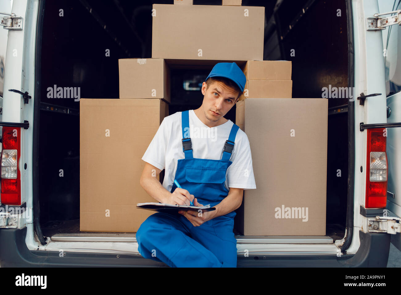 Deliveryman in Uniform, Pakete im Auto, Cargo Stockfoto