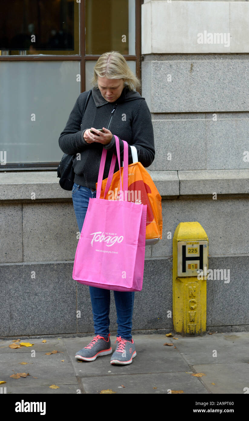 Frau einkaufen hält Ihr Mobiltelefon zu prüfen. Stockfoto