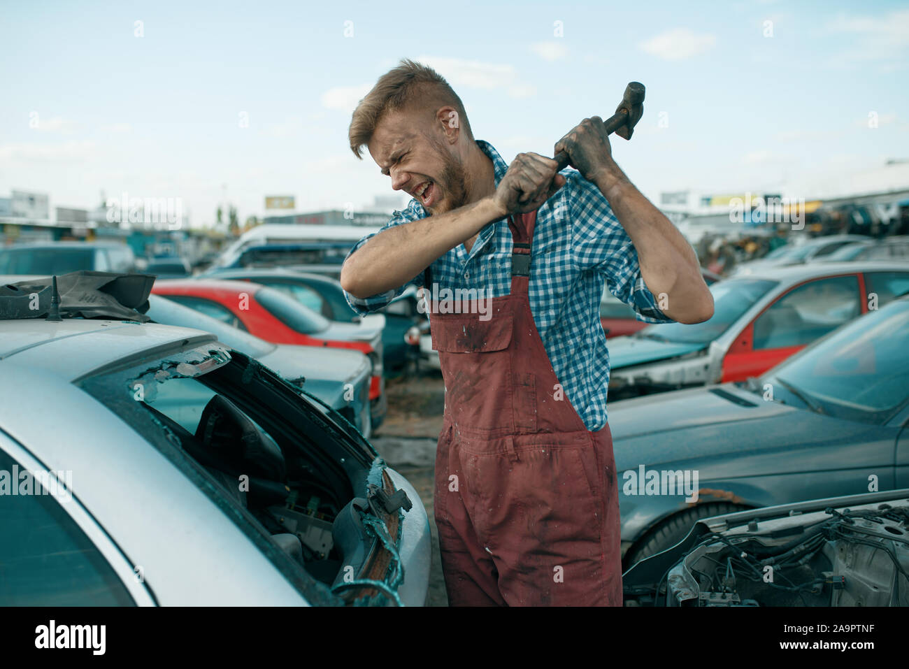 Handwerker Hits das Glas mit Hammer, Auto junkyard Stockfoto