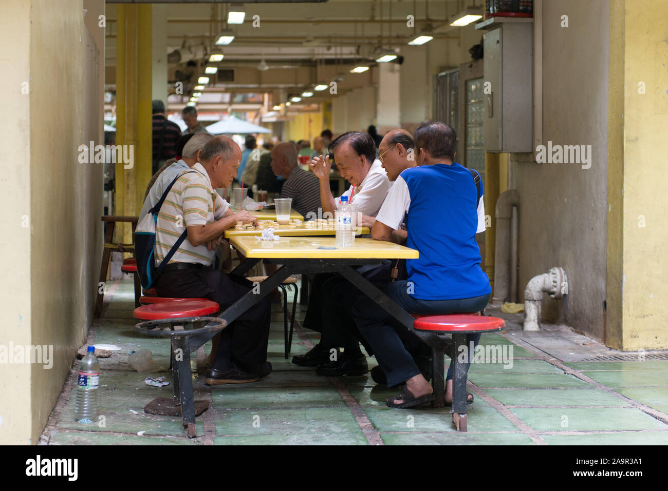 Eine Gruppe von Männern spielen Spielsteine in einer Hawker Center in Singapur Stockfoto
