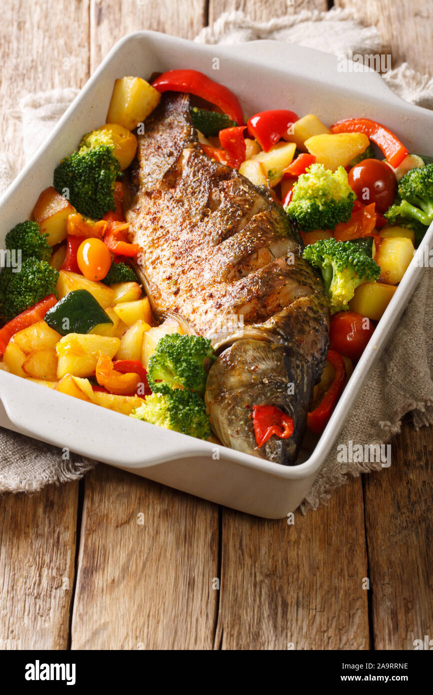 Fluss Fisch gebackene Karpfen mit Gemüse close-up in einer Auflaufform auf den Tisch. Vertikale Stockfoto