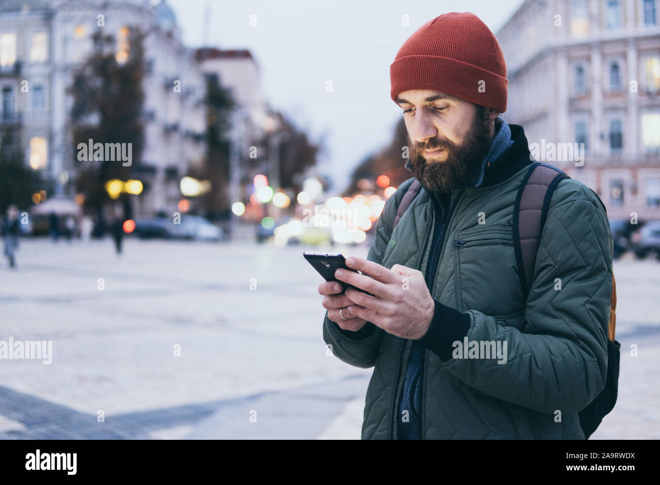 Junge Bartgeier kaukasischen Mann suche auf Mobiltelefon beim Gehen auf die Straße Stockfoto