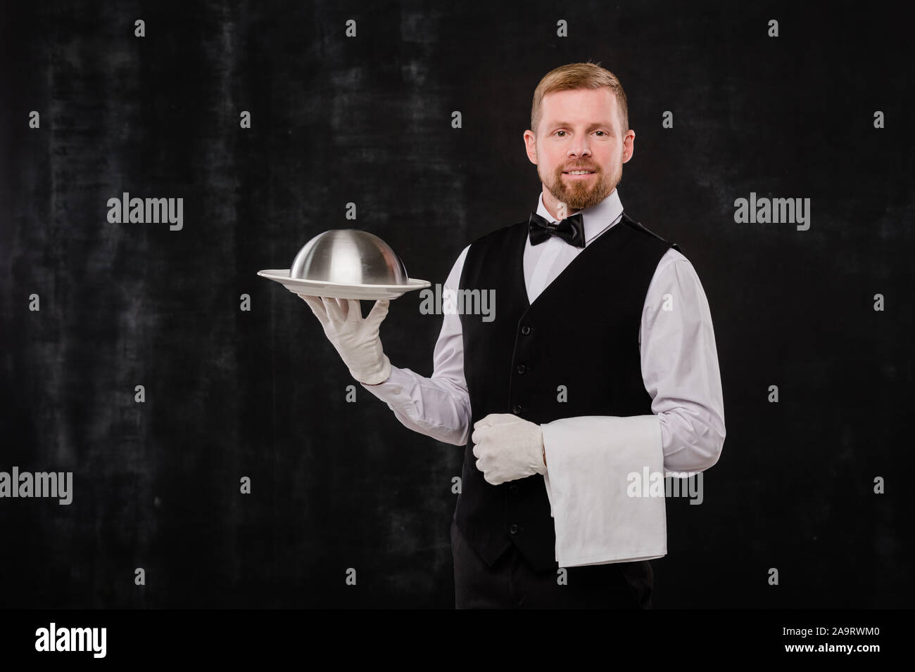 Happy Elegant Kellner der noblen Restaurant holding Handtuch und Cloche mit Nahrungsmitteln Stockfoto