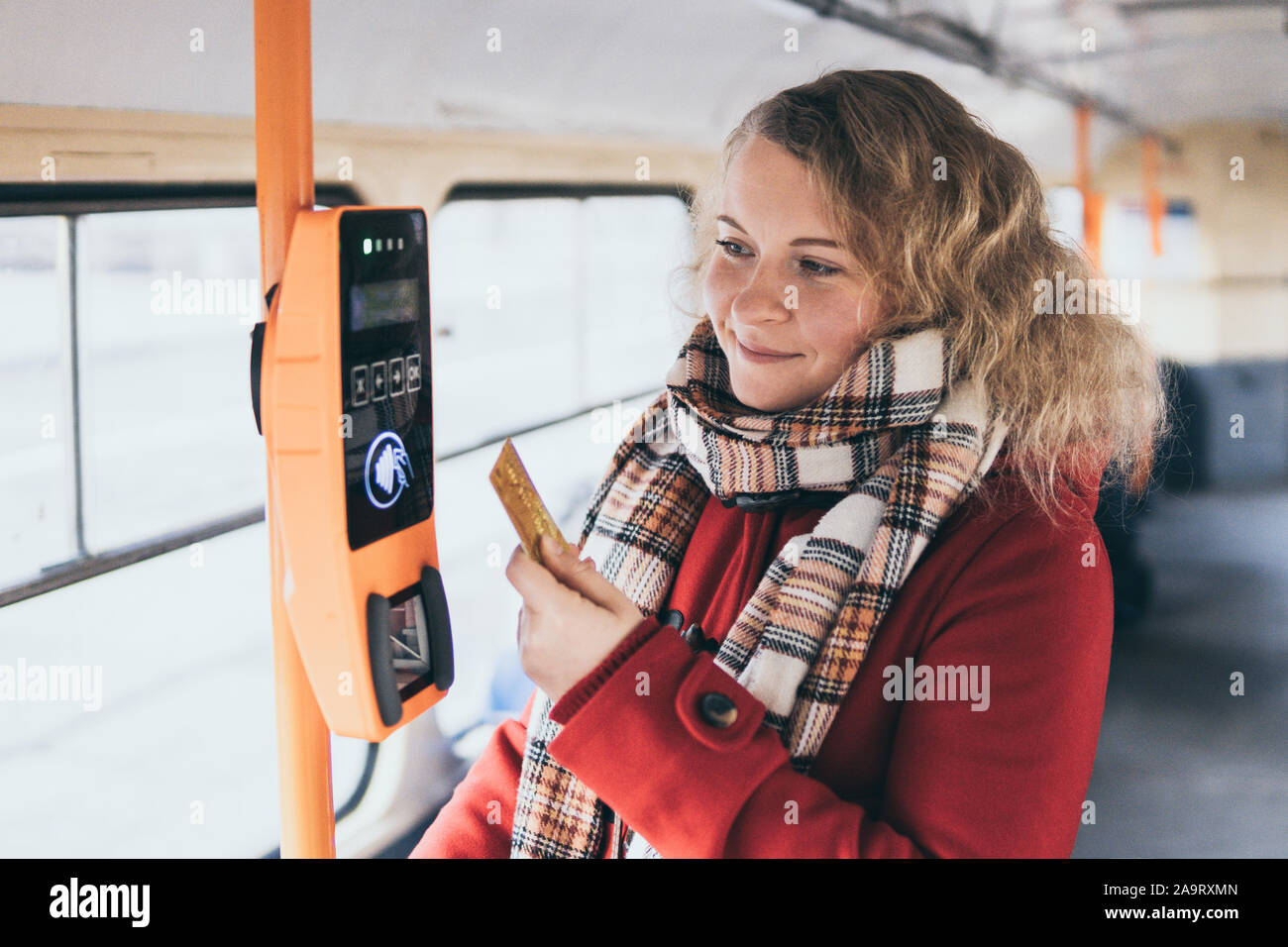 Junge blonde kaukasische Frau bargeldlose Zahlung des öffentlichen Verkehrs Fahrpreises bei automatischen Kontaktlosen Maschine mit einer Karte Stockfoto