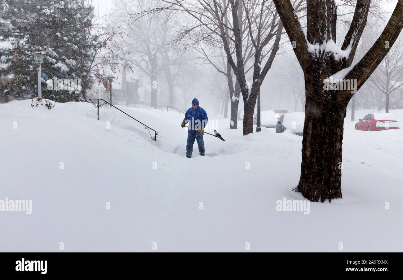 Eine Person schneeschaufeln aus dem Bürgersteig während eines Schneesturmes Blizzard im Stadtzentrum von Saint Paul, Minnesota. Stockfoto