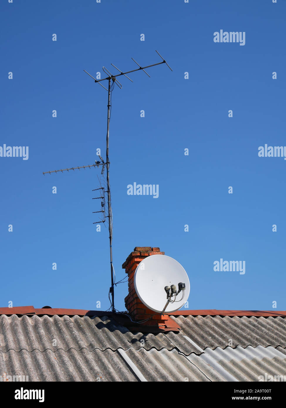 Sat-TV und mehrere terrestrische Antennen auf dem Schiefer Dach eines alten Hauses installiert auf dem Hintergrund einer wolkenlosen blauen Himmel Stockfoto