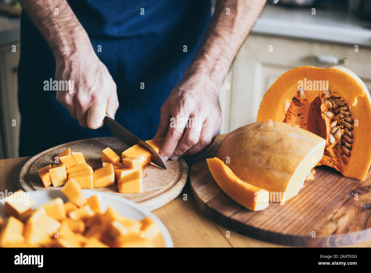 Mann schneidet orange Kürbis in der Küche zu Hause. Stockfoto