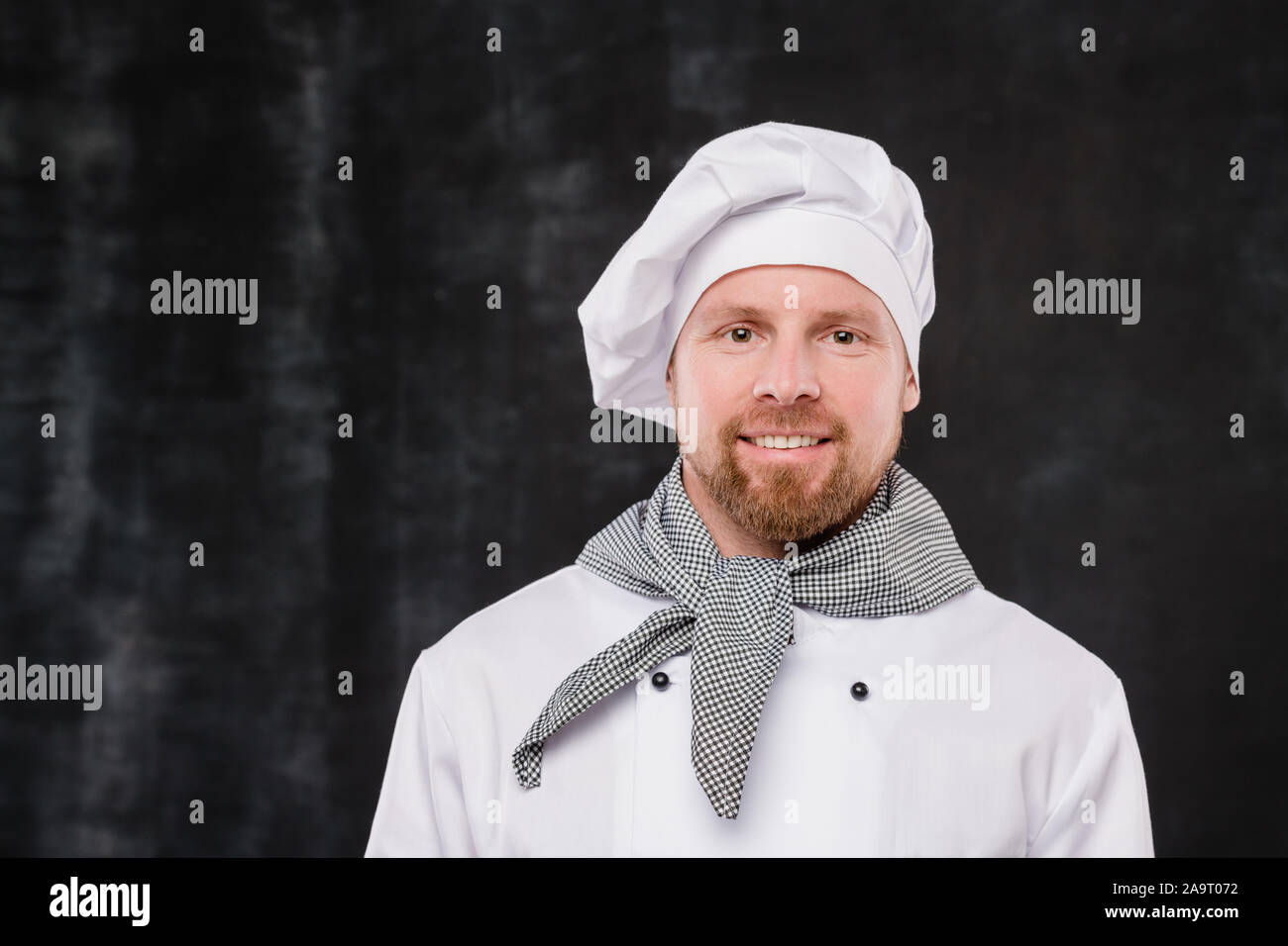 Happy bärtigen Koch in weiße Uniform auf Kamera mit Smile isoliert Stockfoto