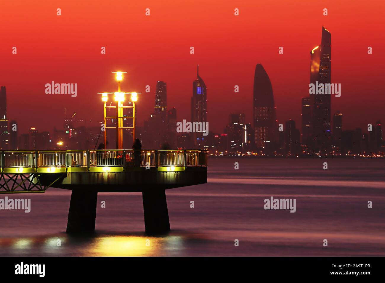 Kuwait City/Kuwait - 10/10/2019: Pier bei Sonnenuntergang mit Skyline Silhouette von Kuwait City im Hintergrund Stockfoto