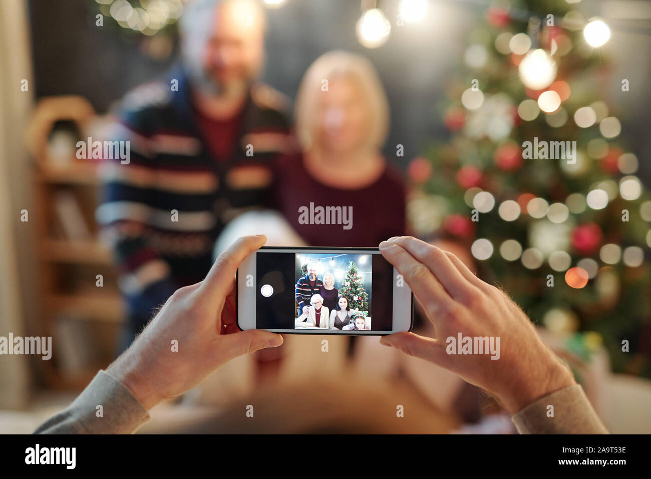 Hände von Mann mit Smartphone unter Foto von großen entspannt Familie Stockfoto